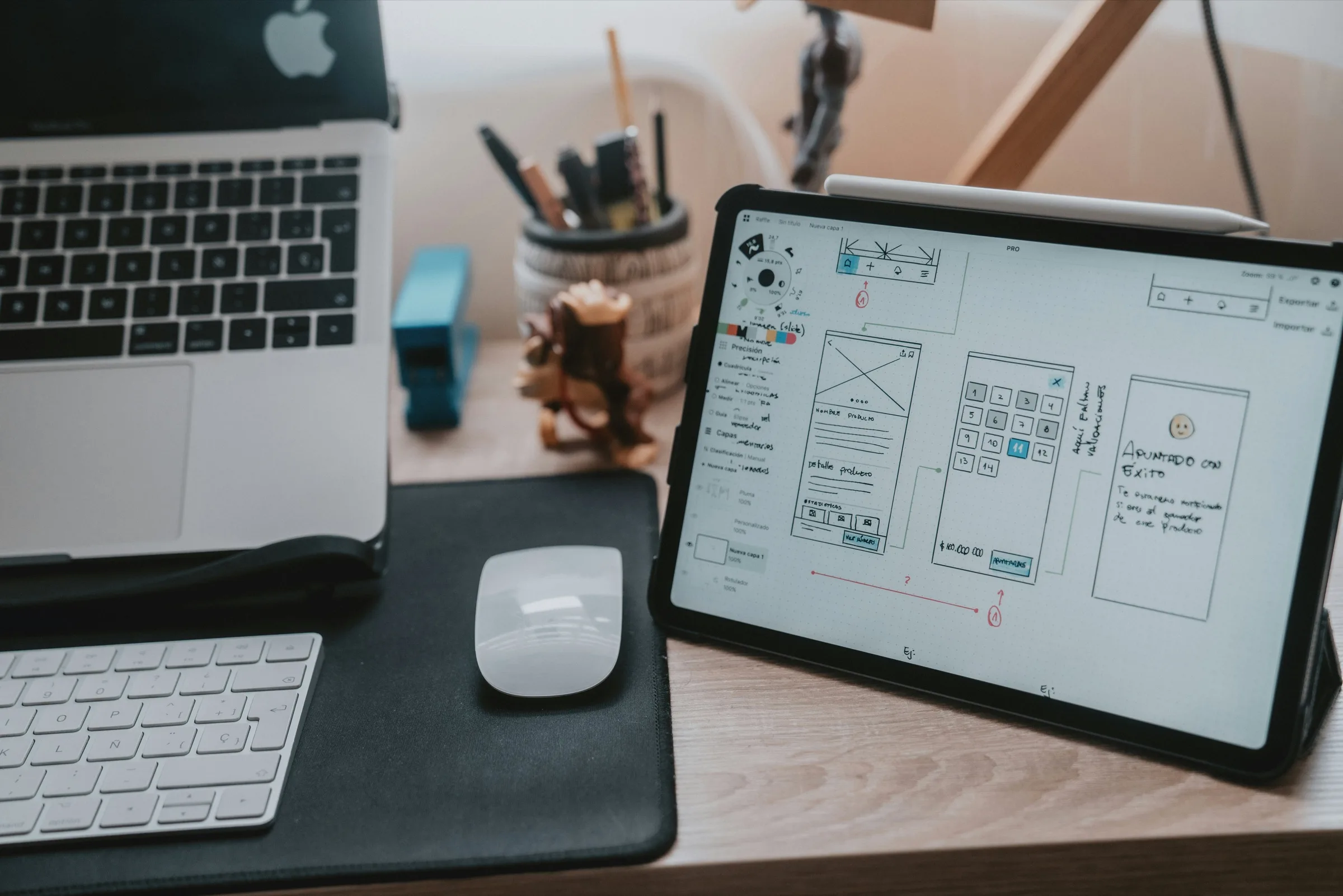 A desk with a laptop and a tablet showing interface wireframes